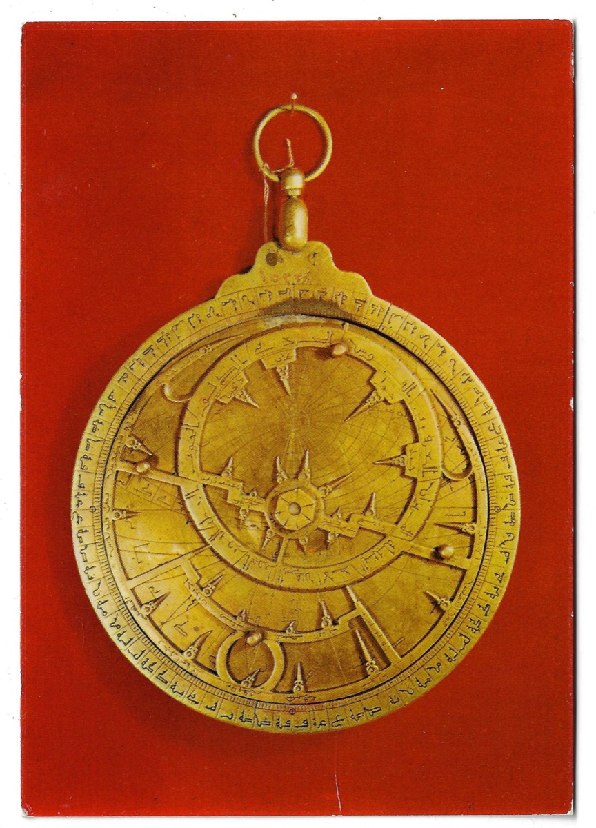 A postcard: a brass astrolabe engraved in Arabic, photographed against a deep red ground, captioned National Museum of Damascus, Astrolabe, sixteenth century.