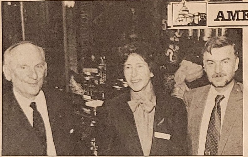 Professor Zdzislaw Zygulski Jr. on the left, a guest in the centre, and Nabi Israfil on the right, standing in the gallery among chandeliers and shelves of metalwork.