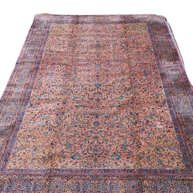 An antique Royal Kirman carpet: a rose field of flowering vines within a deep indigo border.