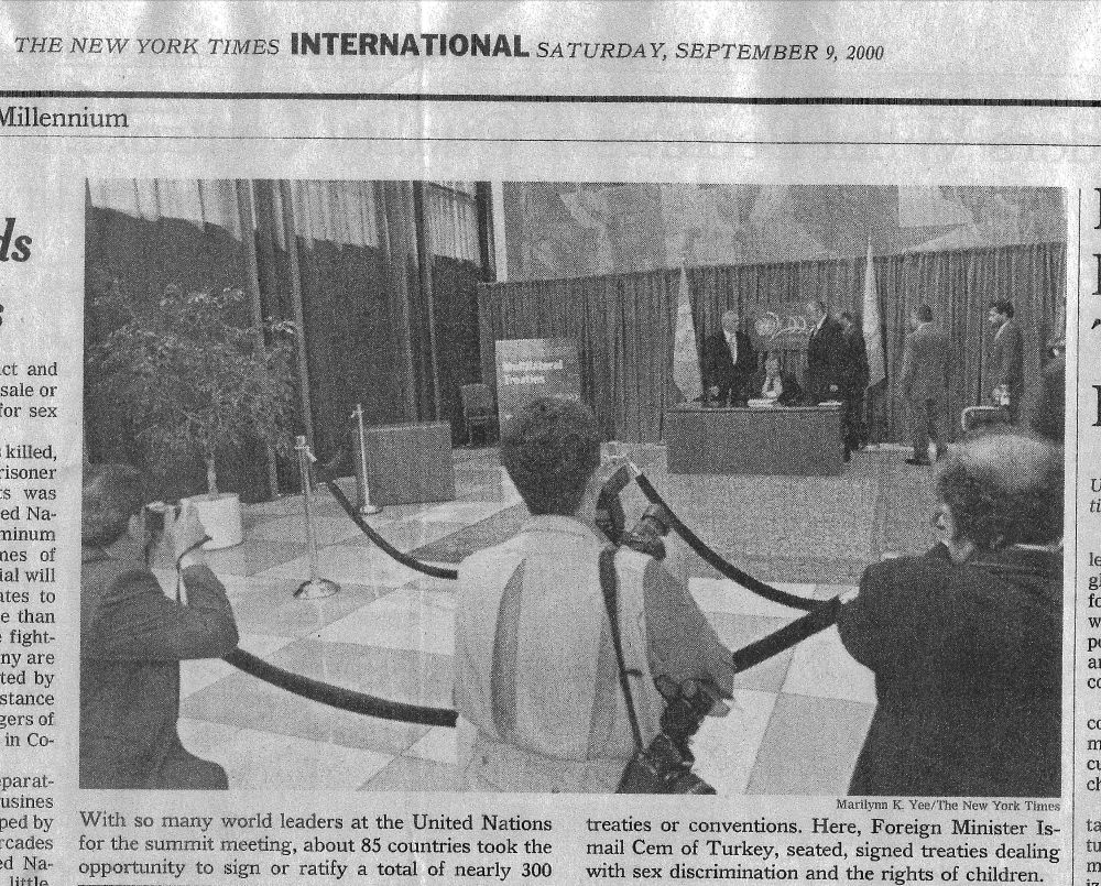 A newspaper clipping headed The New York Times International, Saturday, September 9, 2000, over a photograph of press photographers at a rope line in a United Nations lobby, with the treaty signing table beyond them and a seated signatory at the table.