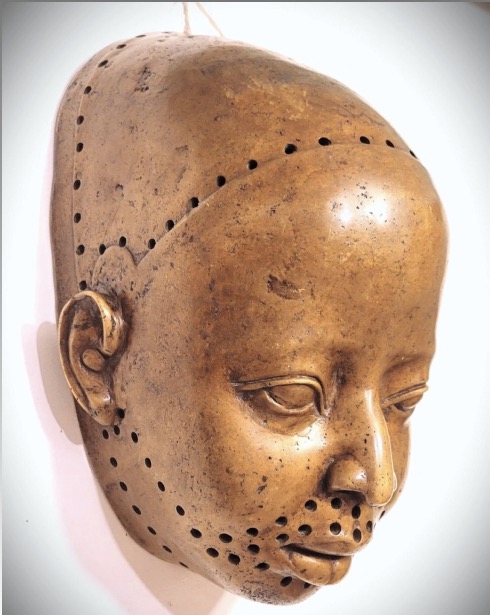 Yoruba Ife bronze mask in three-quarter view, its serene face bordered by rows of small perforations