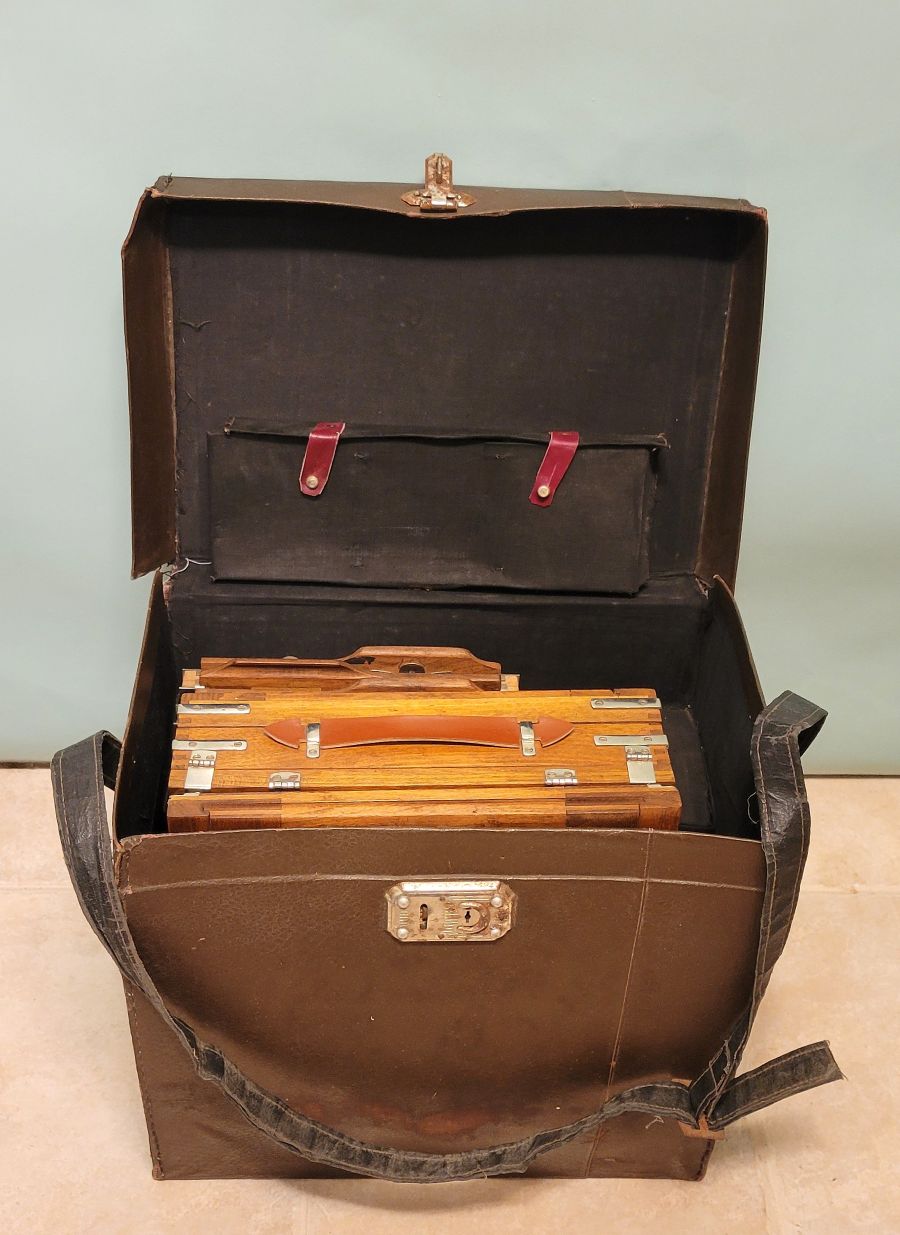 Antique folded wood large-format plate camera resting in its leather carrying case